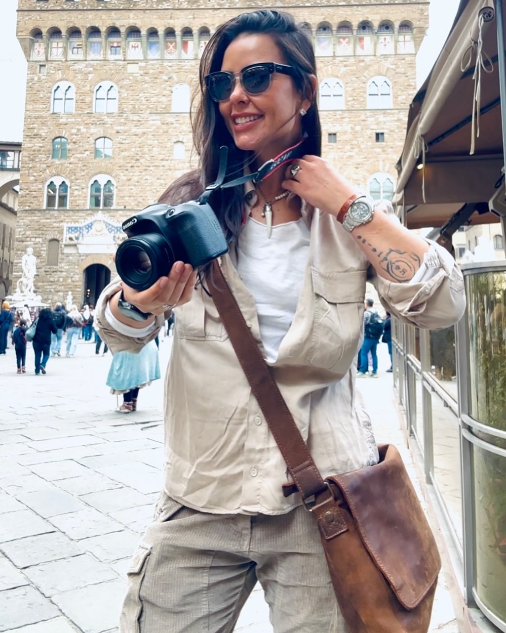 Regiane Severini em uma praça histórica italiana, segurando sua câmera
